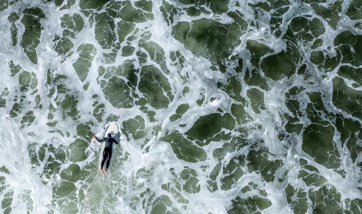April 2025 photo of a surfer paddling out at the Huntington Beach pier.