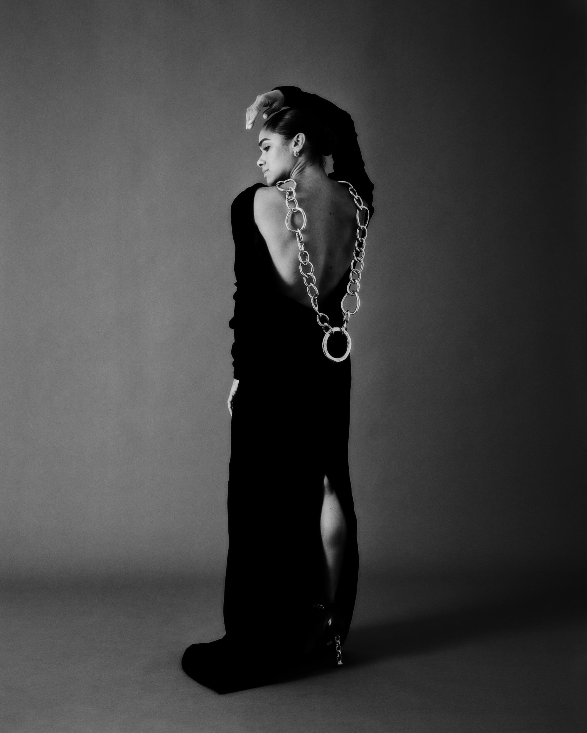 Copeland faces her back to us, a long chain necklace dangling down her back.