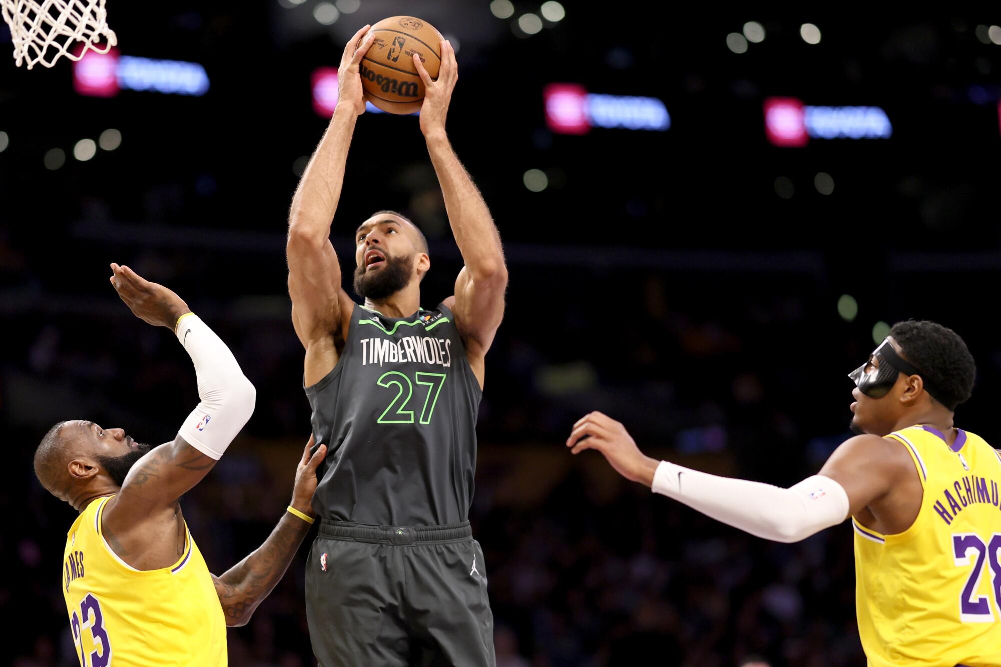 Timberwolves center Rudy Gobert shoots in front of Lakers forwards LeBron James and Rui Hachimura.