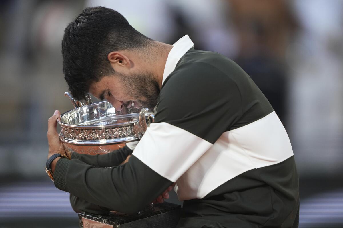 Spain's Carlos Alcaraz hugs the trophy and bows his head after winning the French Open against Italy's Jannik Sinner.