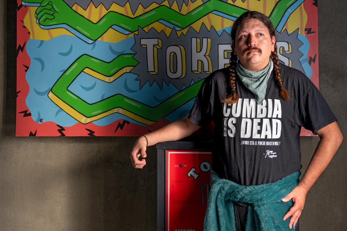 Poltergeist chef Diego Argoti stands next to an arcade token machine in Button Mash in 2023.