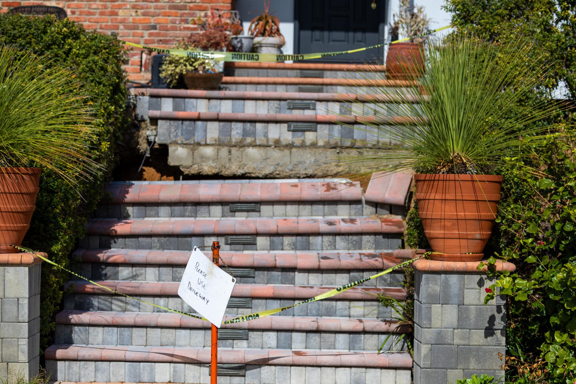 Front steps have cracked and dropped nearly a foot at a home with yellow caution tape in front of it.