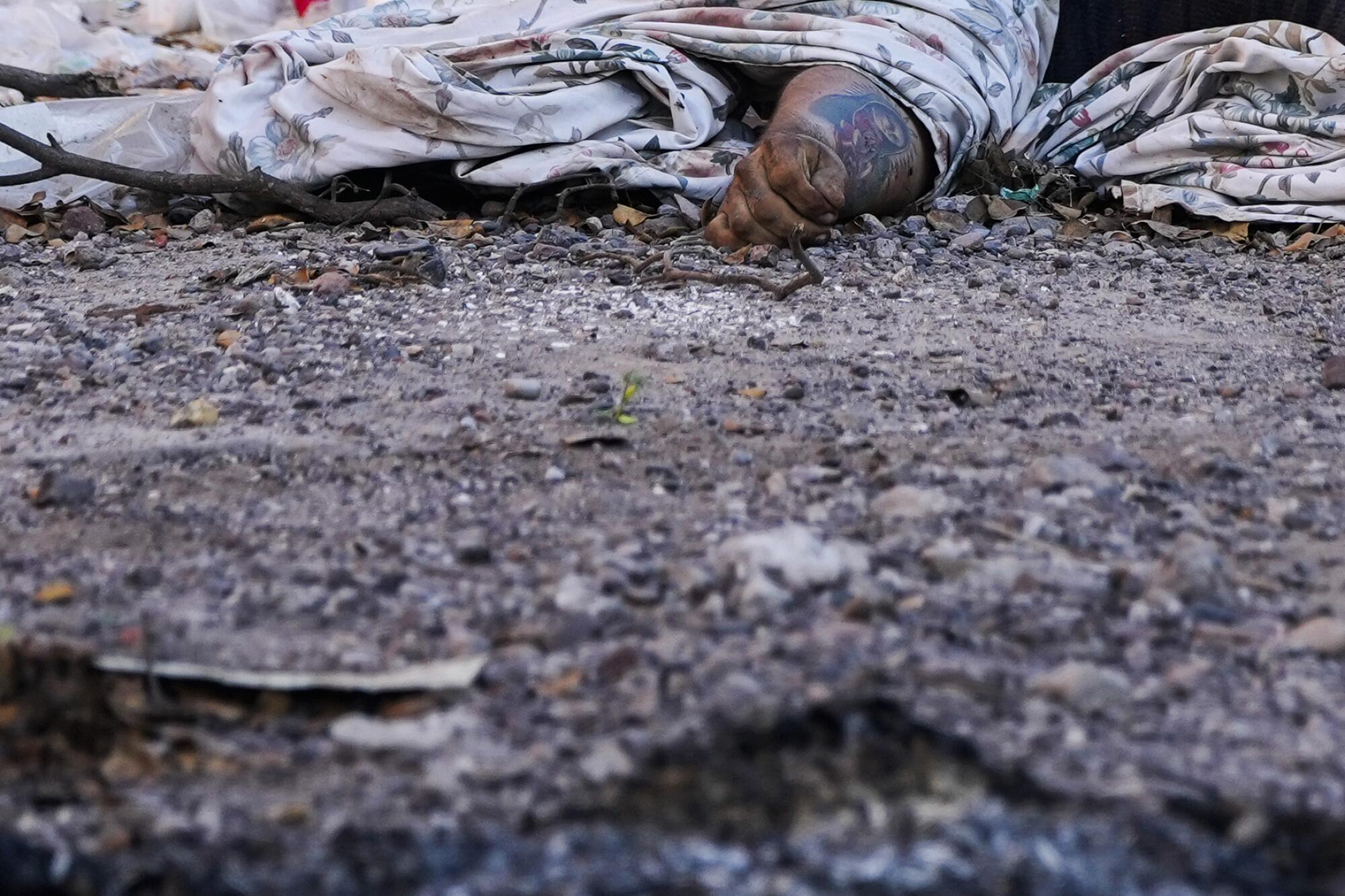 A dead man's body lying under a tarp on a dirt road