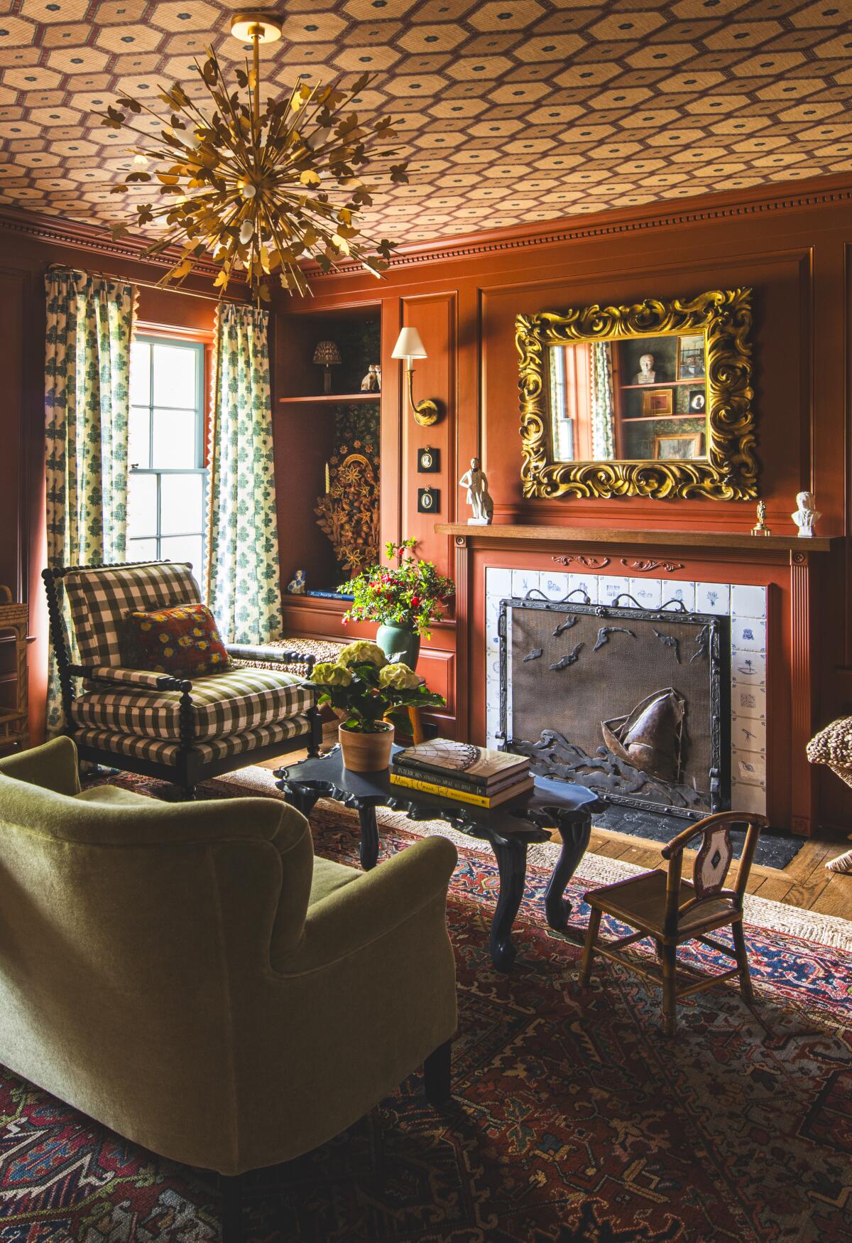 A colorful library and fireplace with comfy chairs and antiques