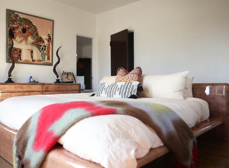 A platform bed with a colorful blanket in a room in beiges and browns