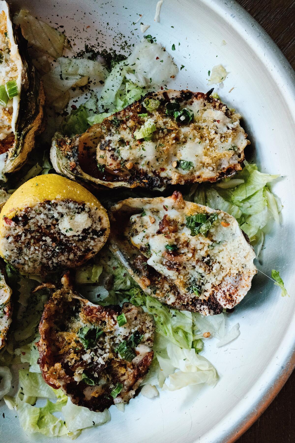 Charbroiled oysters at Evangeline Swamp Room in Chinatown. At center is a charred half of a lemon.
