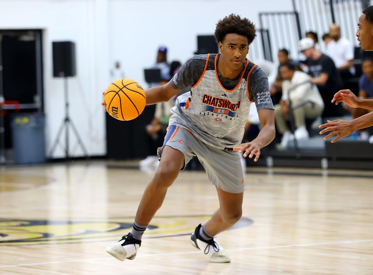 Alijah Arenas leans forward and dribbles the basketball on a court inside a gym.
