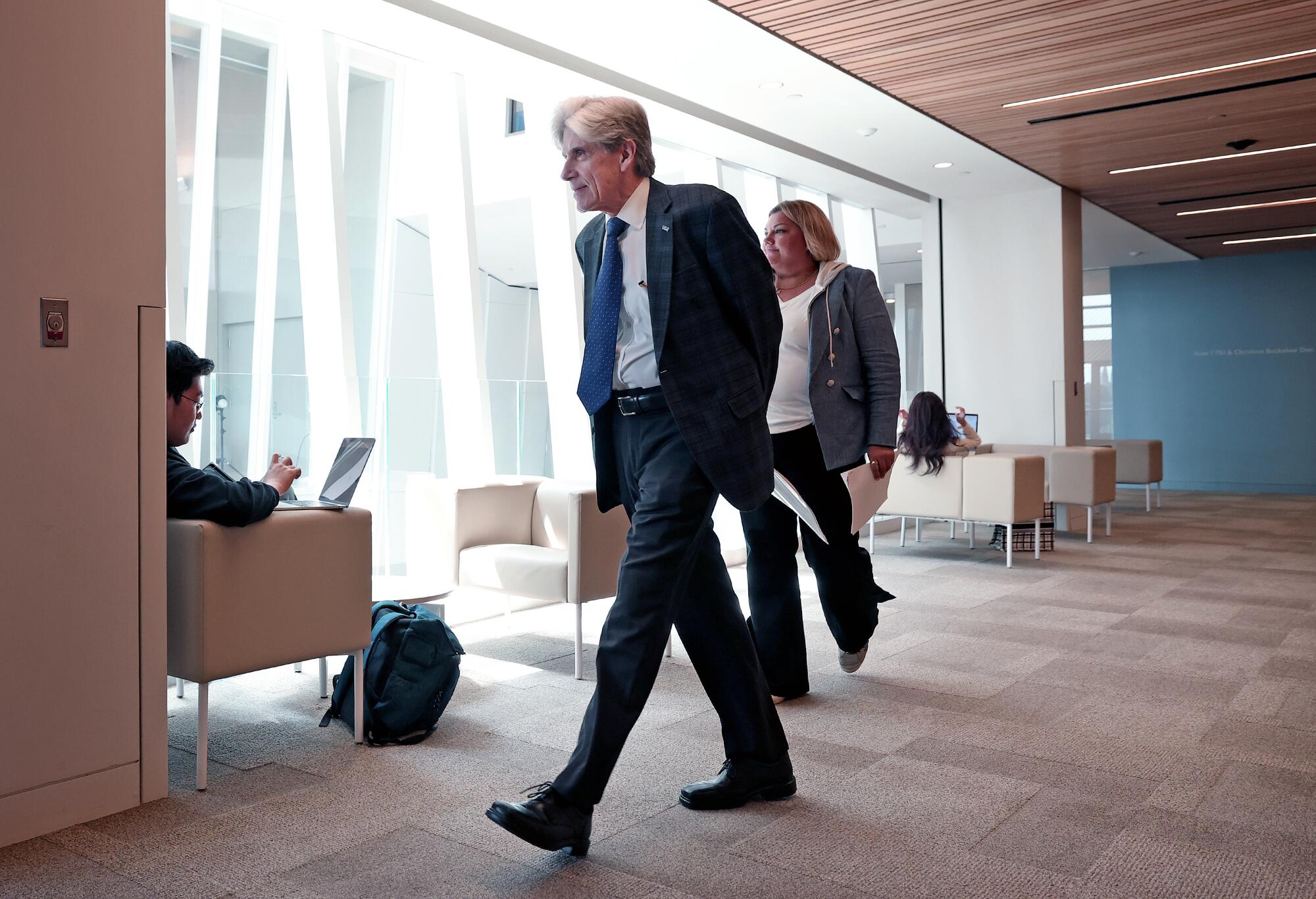 UCLA Chancellor Julio Frenk walks past chairs and windows at the Anderson School of Management