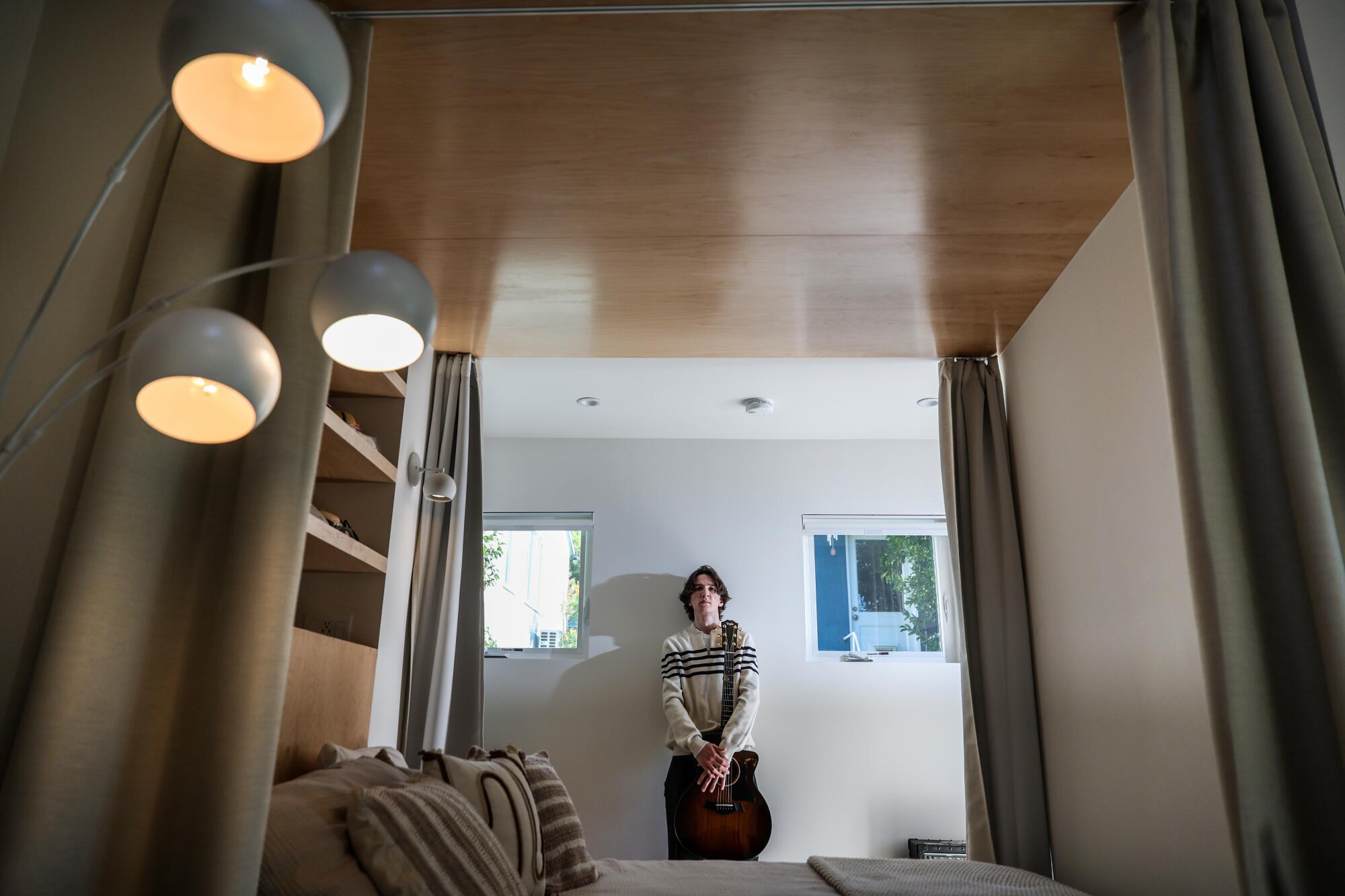 A young man stands on the side of a bed niche