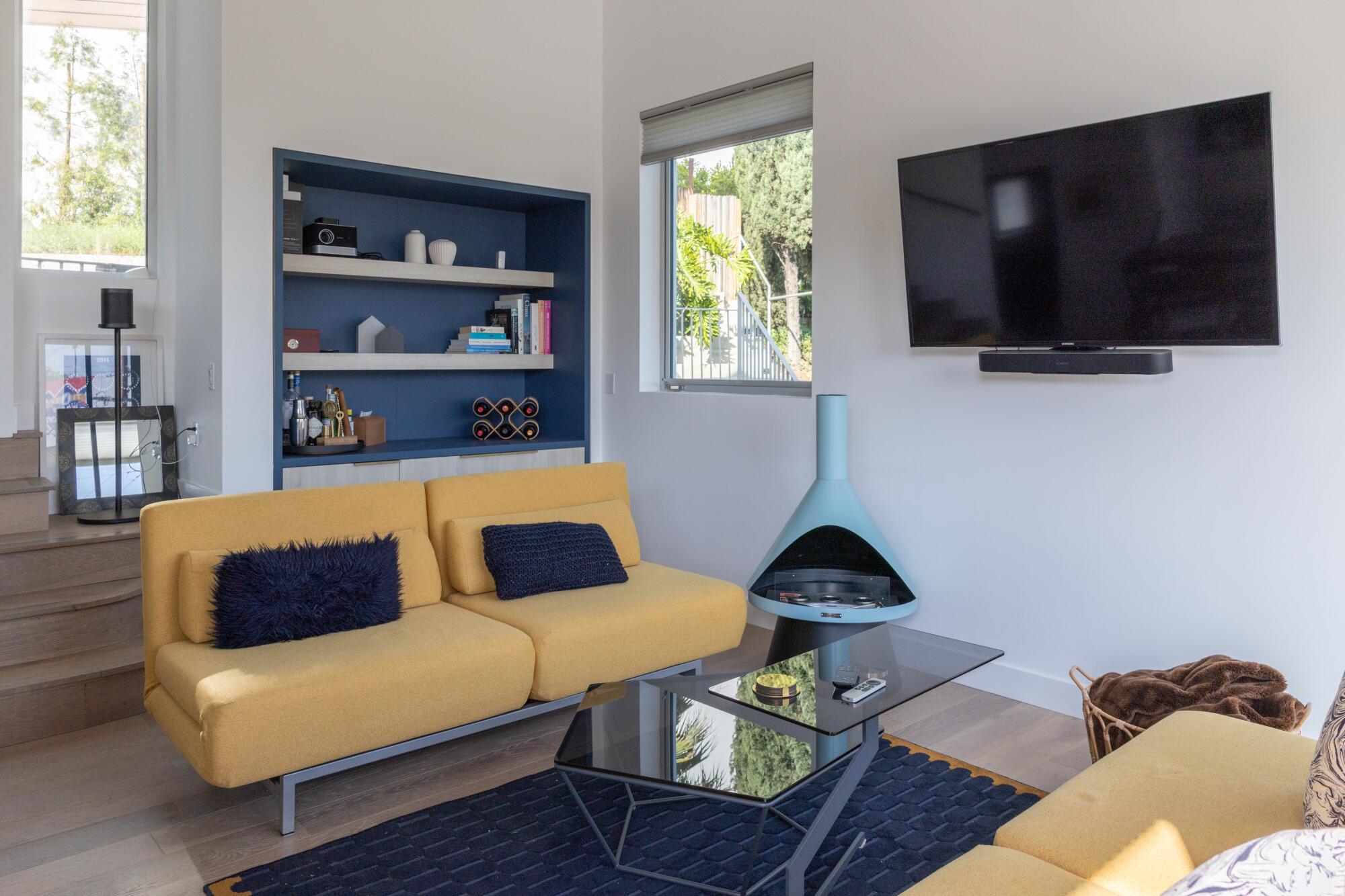 Two yellow sofas, a blue firepit and TV