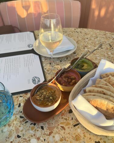 Dishes of food, a glass of wine and an open menu on a restaurant table