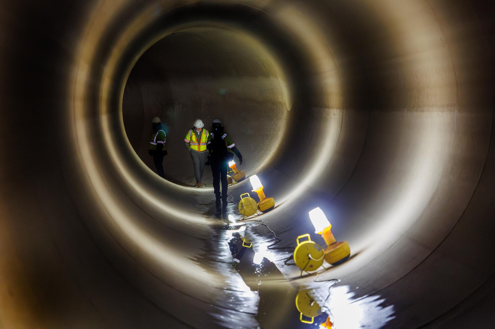 People walk in a tunnel with a small amount of water running through it
