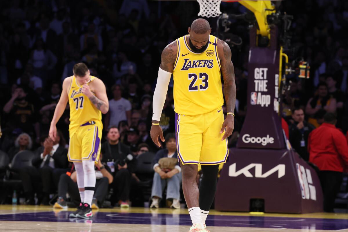 Luka Doncic and LeBron James walk across the court with their heads down.