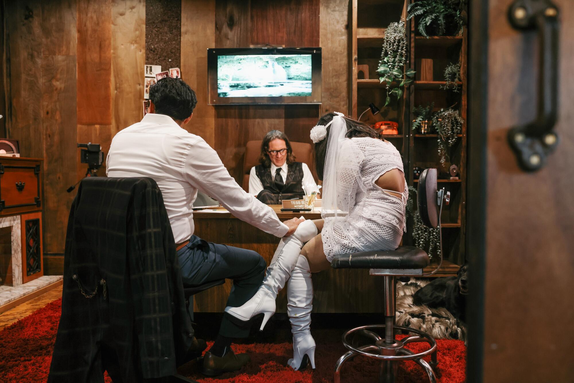 A couple write their vows in an office as another man sits behind a desk