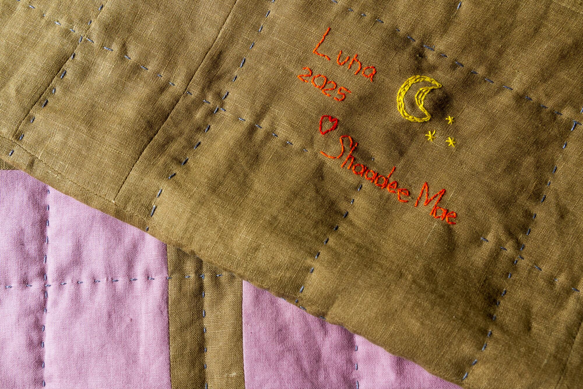 A quilt is signed on the back with an embroidered name