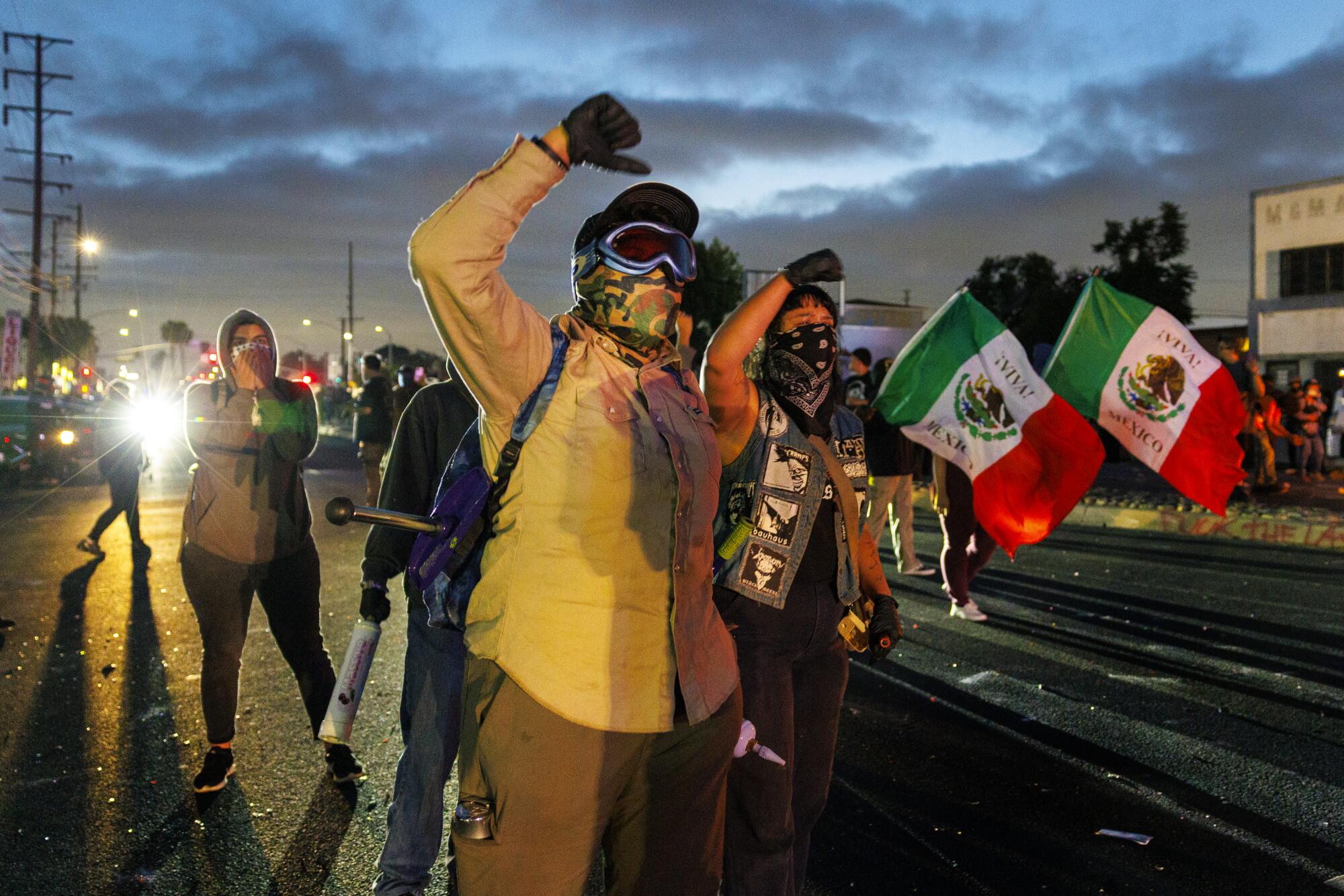 Protesters with their hands in the air next to two Mexico flags.