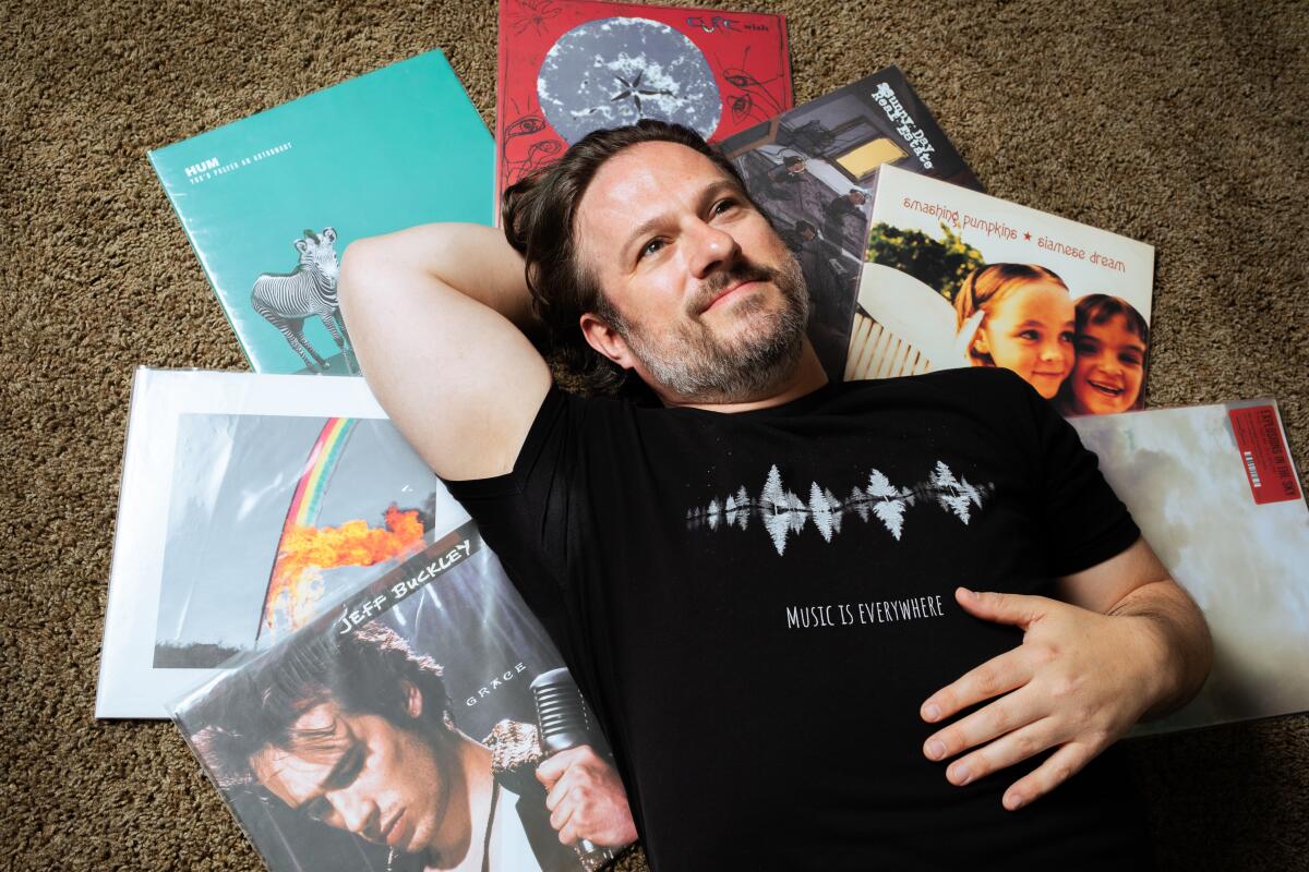 Man laying down on a pile of 90s vinyl records