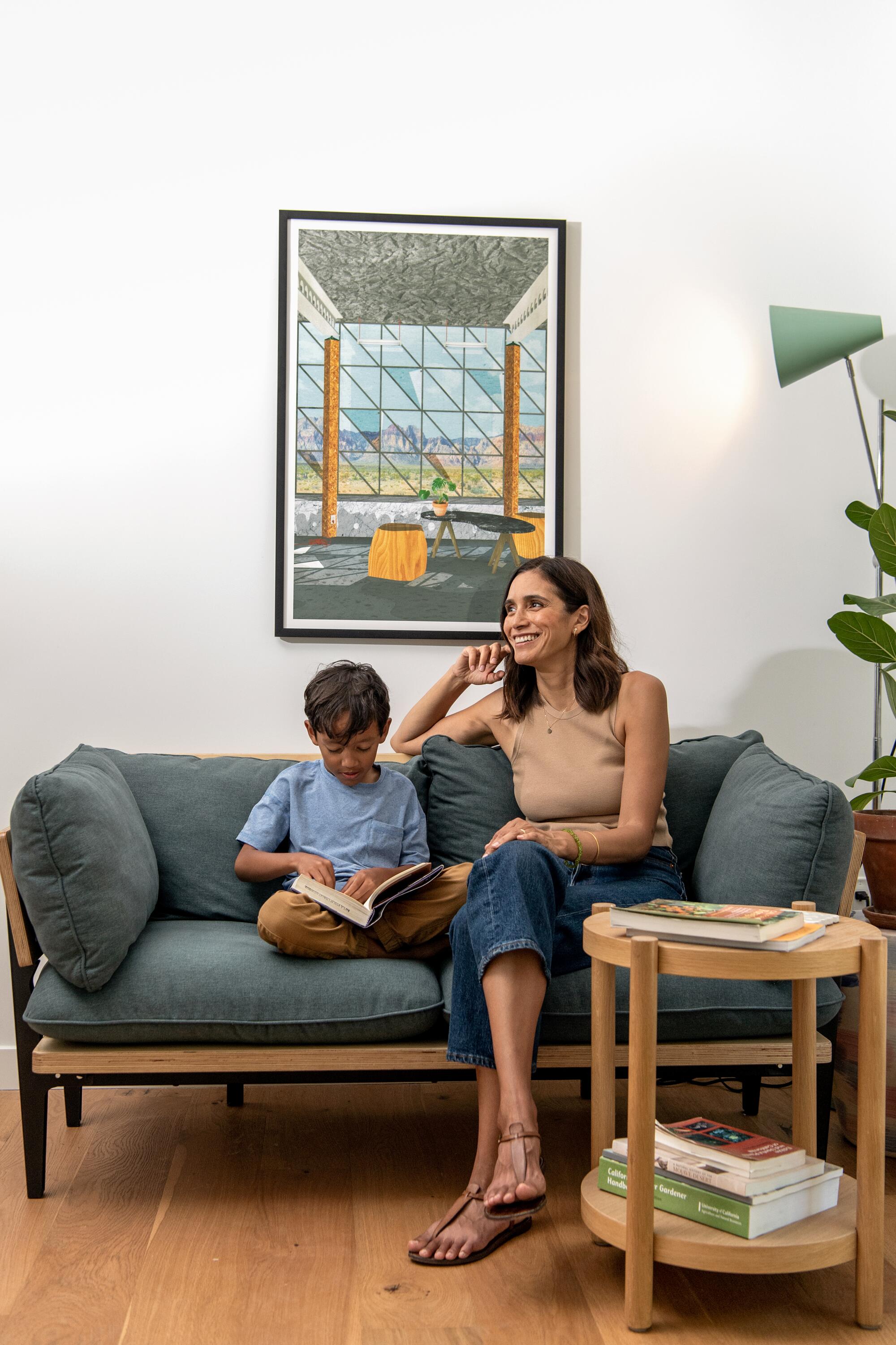 A woman sits with her young son on a gray couch.
