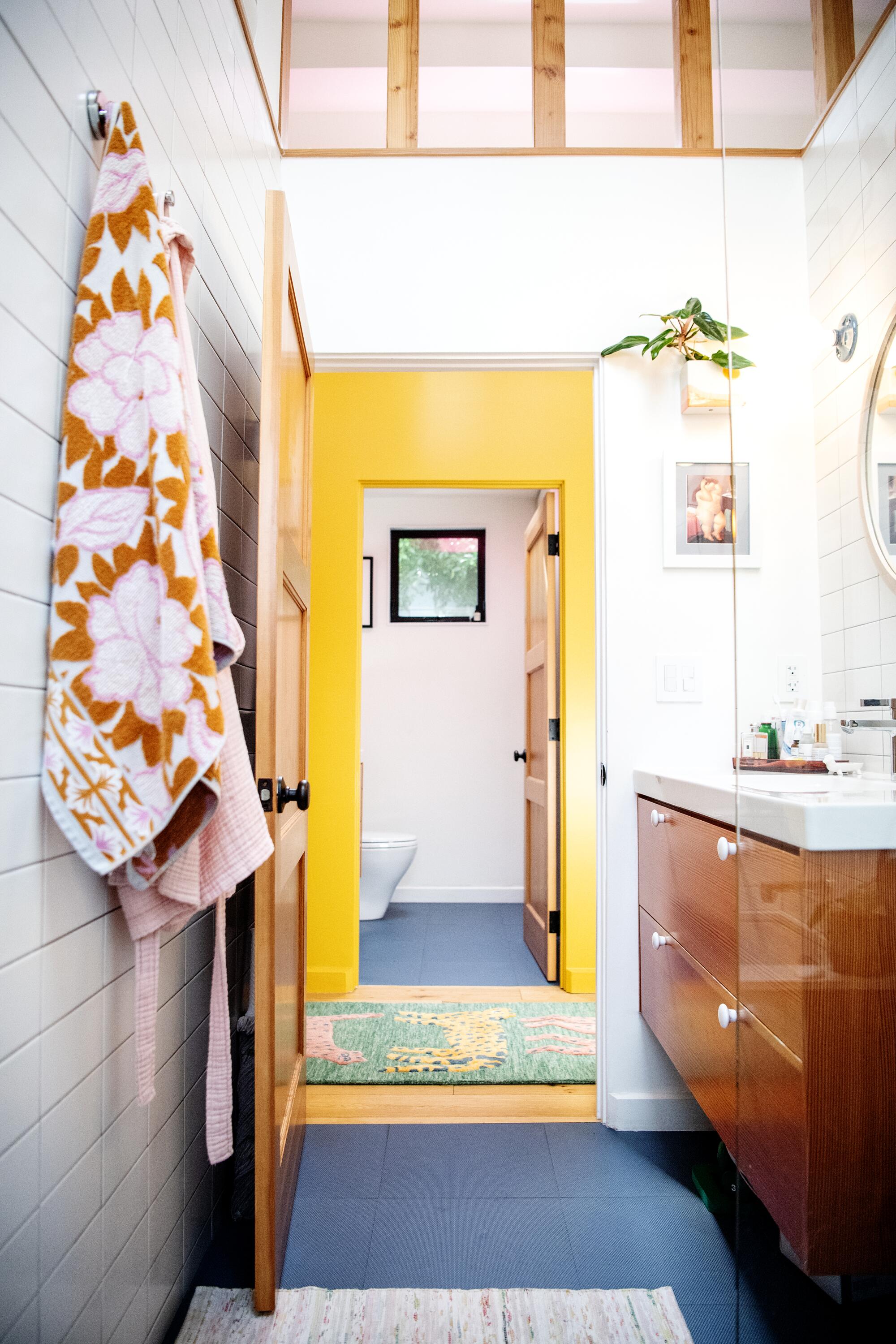 A view from a bathroom with a vanity and sink into the room across the hall with the toilet.